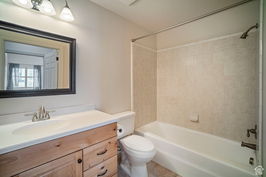 Full bathroom featuring toilet, tiled shower / bath combo, a textured ceiling, vanity, and tile flooring