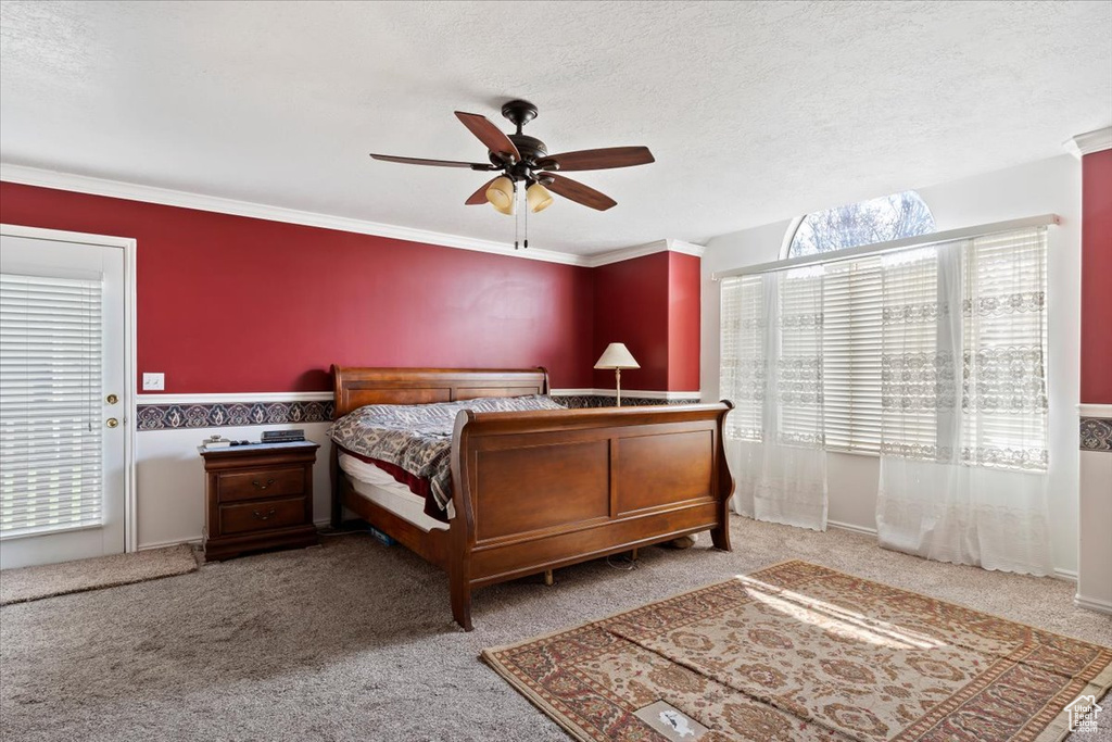 Bedroom featuring a textured ceiling, crown molding, ceiling fan, and light colored carpet