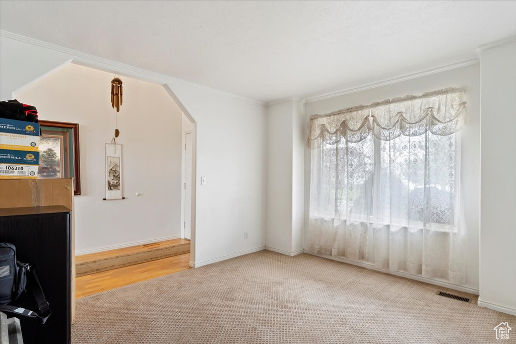 Unfurnished room with crown molding and light wood-type flooring