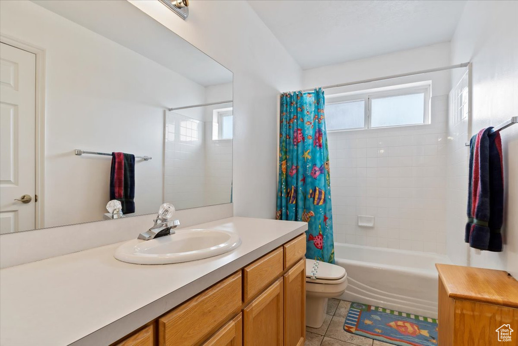 Full bathroom with tile floors, vanity with extensive cabinet space, toilet, and shower / bathtub combination with curtain