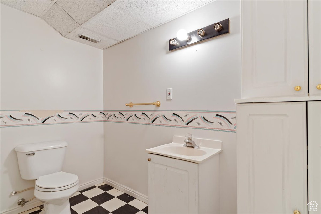 Bathroom with a drop ceiling, tile flooring, toilet, and vanity