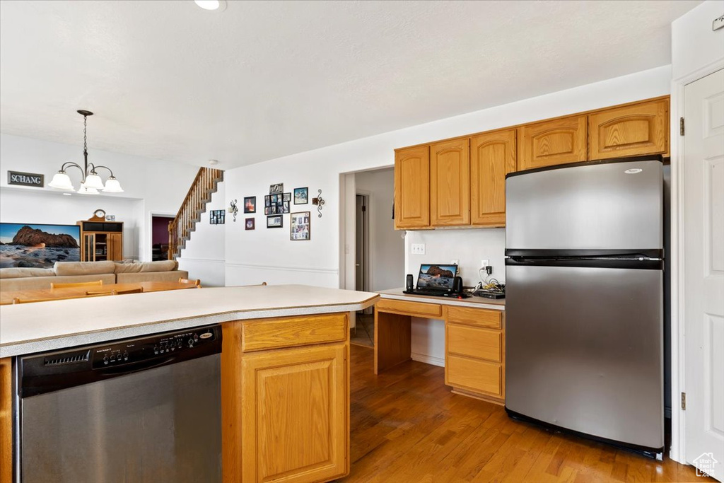 Kitchen featuring a notable chandelier, appliances with stainless steel finishes, hanging light fixtures, and light hardwood / wood-style floors
