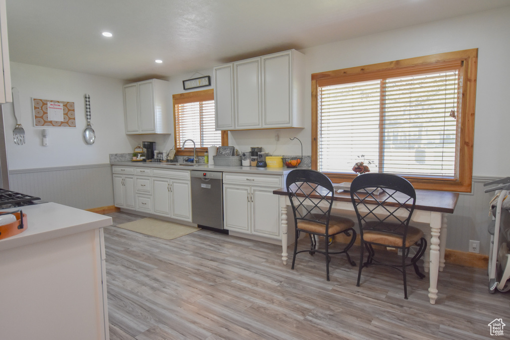 Kitchen with light hardwood / wood-style flooring, white cabinets, and dishwasher