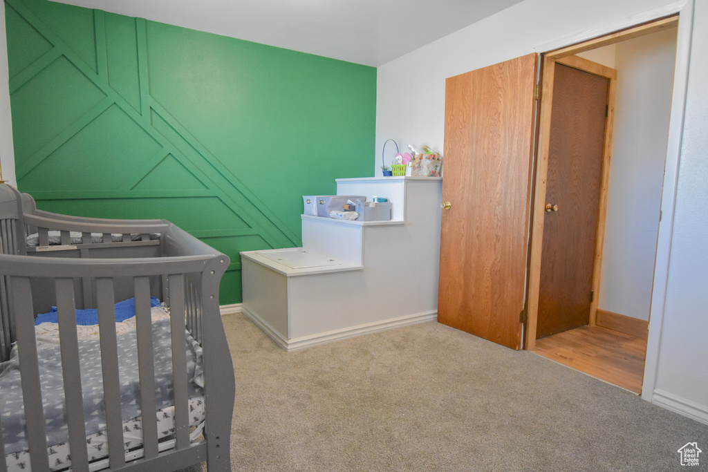 Unfurnished bedroom with light carpet and a nursery area