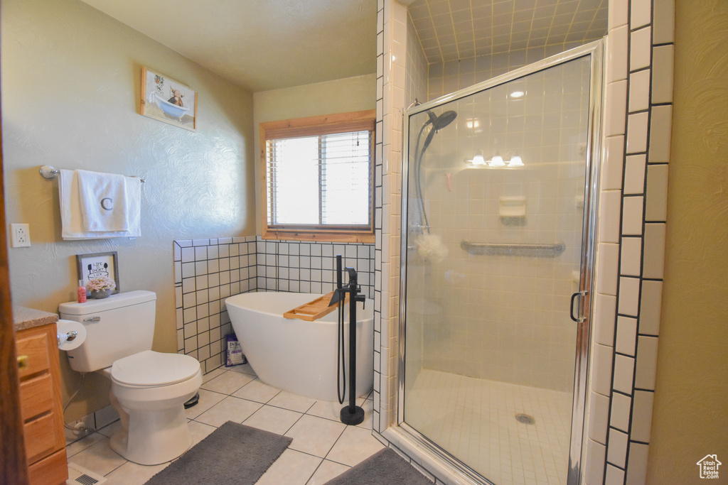Bathroom with toilet, tile floors, a shower with shower door, and vanity