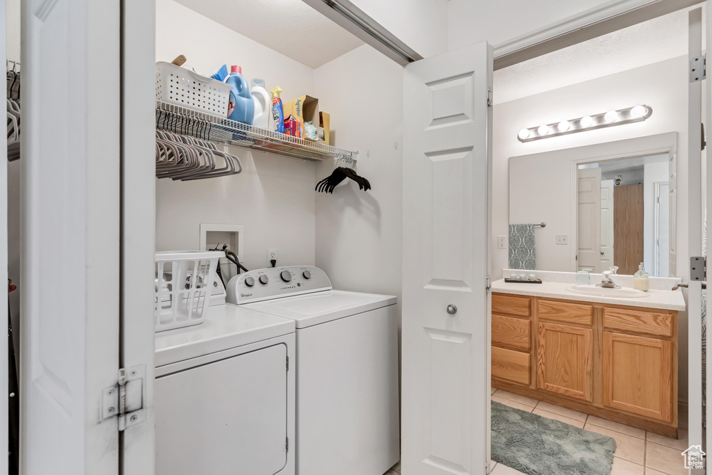 Laundry area featuring washer hookup, washer and clothes dryer, sink, and light tile floors