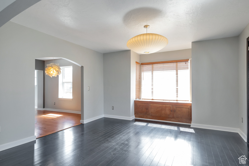 Unfurnished room with plenty of natural light, dark hardwood / wood-style floors, and an inviting chandelier