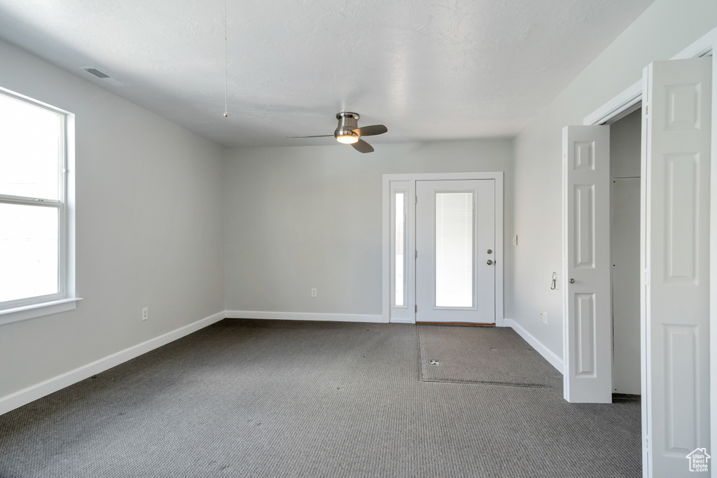 Interior space with a healthy amount of sunlight, ceiling fan, and dark carpet