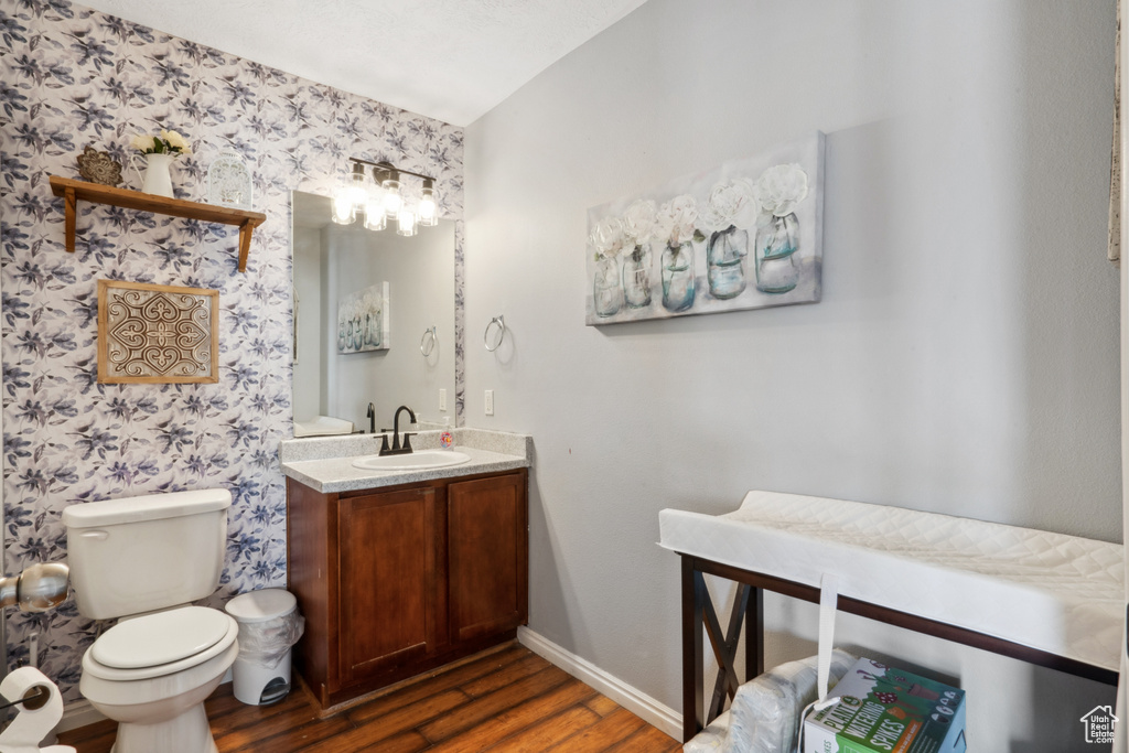Bathroom featuring lofted ceiling, toilet, vanity, and wood-type flooring