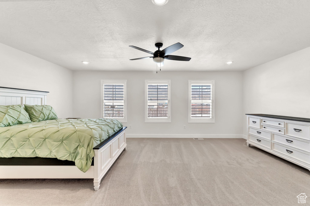 Bedroom featuring ceiling fan, light carpet, and a textured ceiling