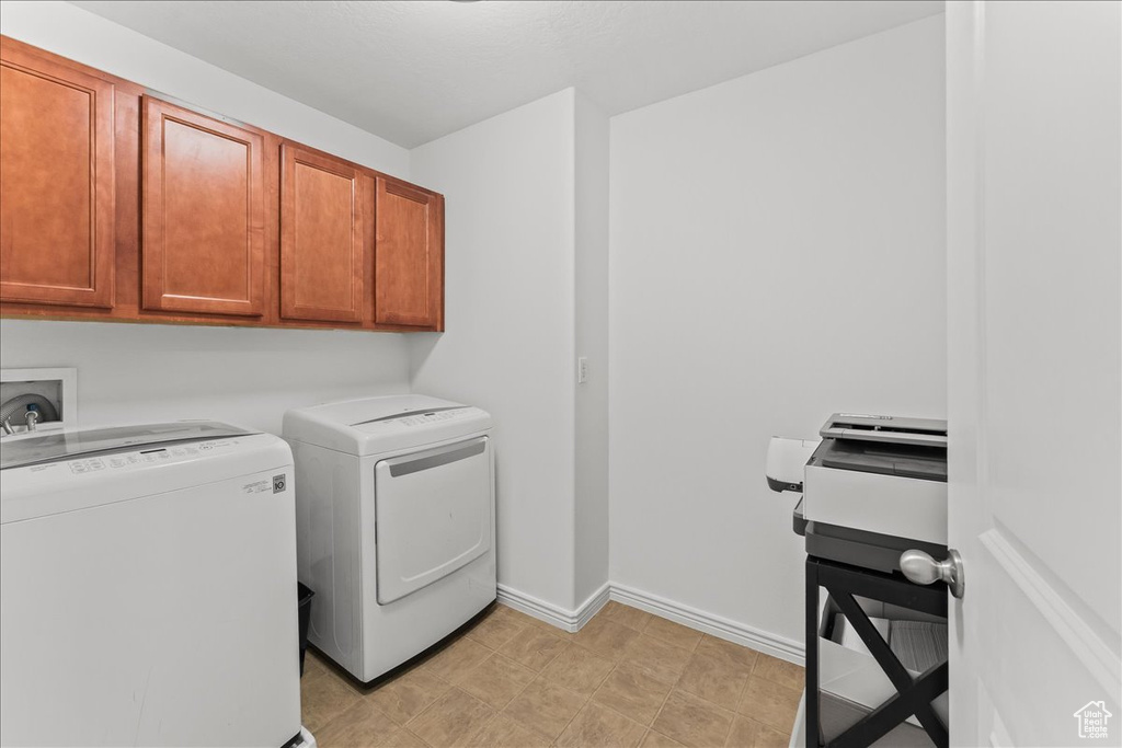 Laundry area with light tile flooring, hookup for a washing machine, washing machine and dryer, and cabinets