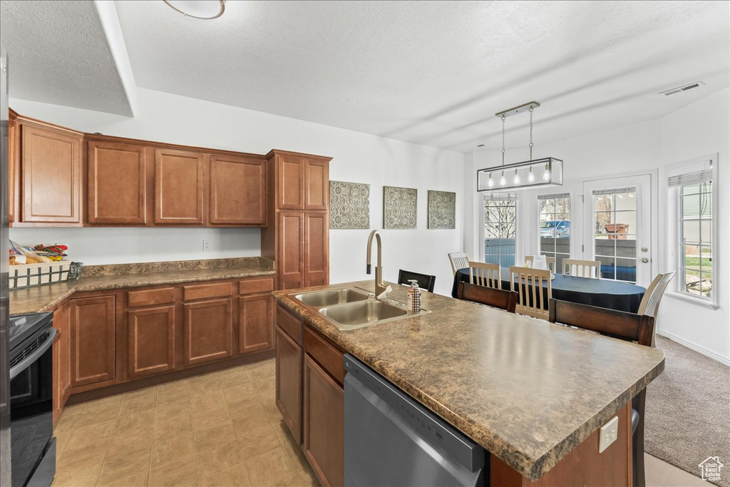 Kitchen featuring a kitchen island with sink, sink, stainless steel dishwasher, light carpet, and decorative light fixtures