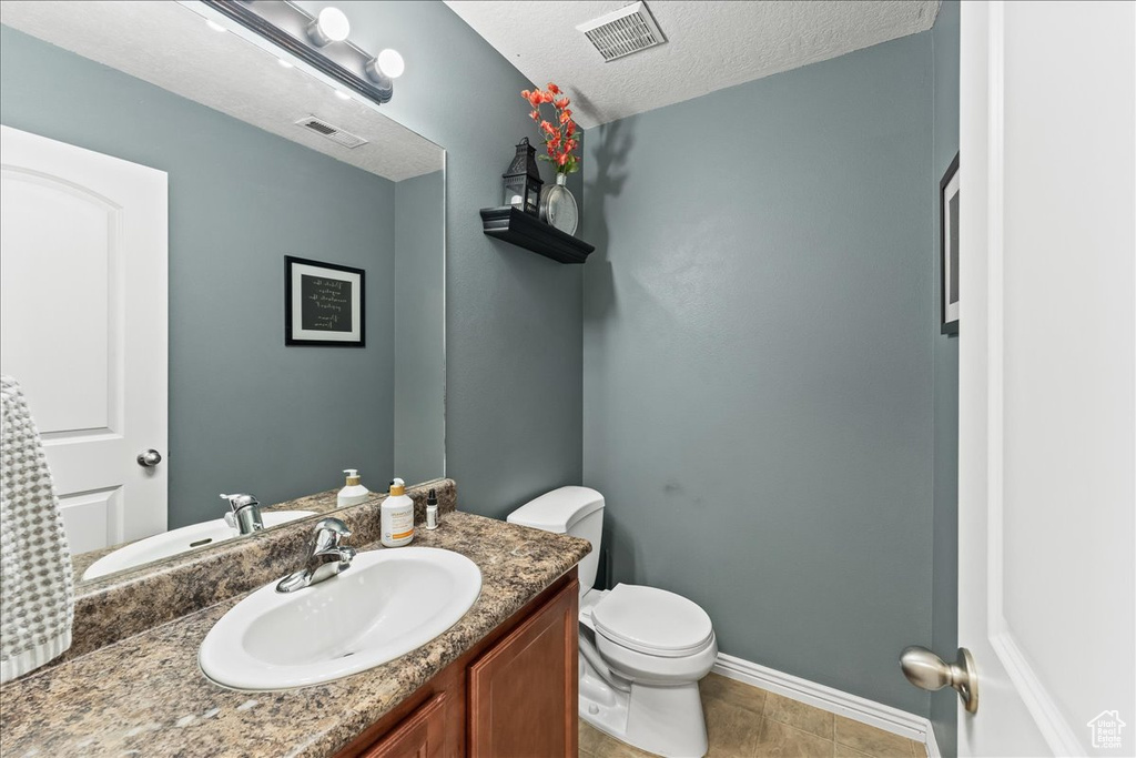 Bathroom featuring vanity, a textured ceiling, tile floors, and toilet