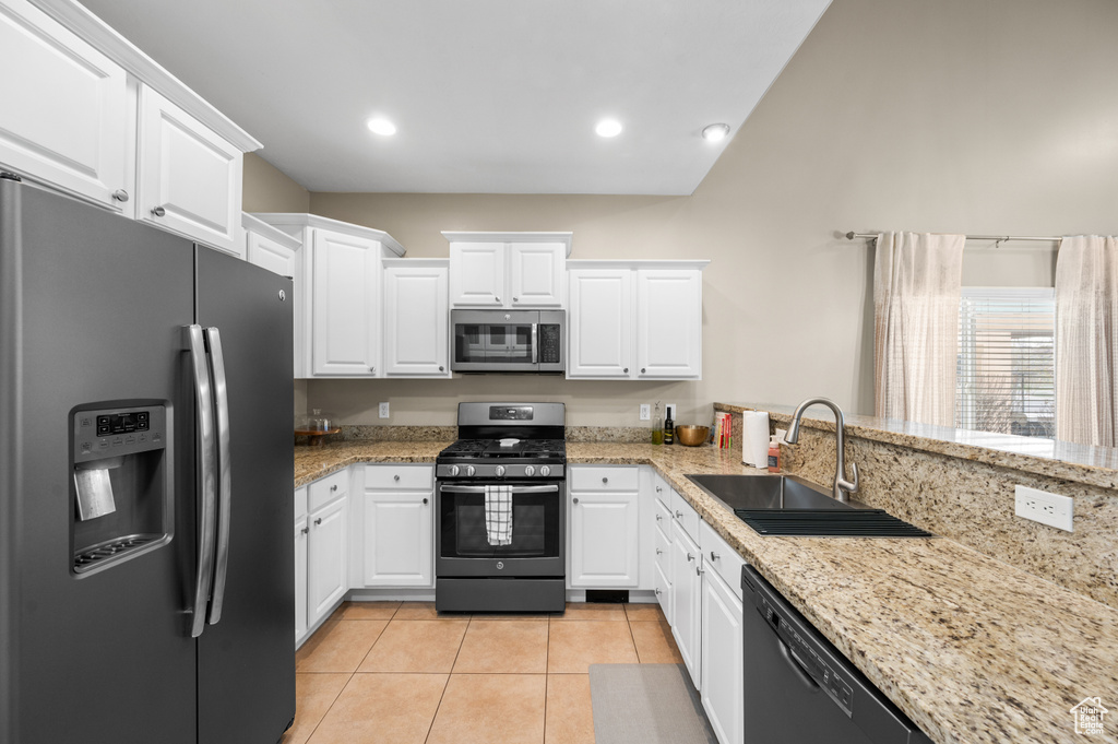 Kitchen featuring appliances with stainless steel finishes, sink, light tile floors, and white cabinets