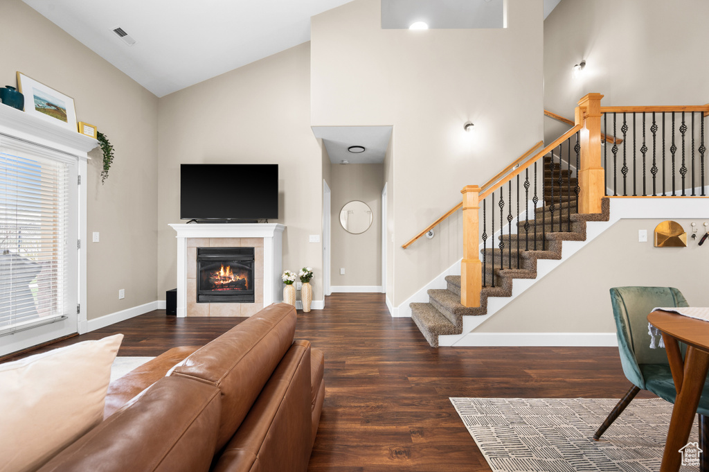 Living room featuring a tiled fireplace, high vaulted ceiling, and dark hardwood / wood-style flooring