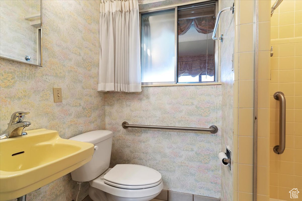 Bathroom featuring sink, toilet, and a tile shower