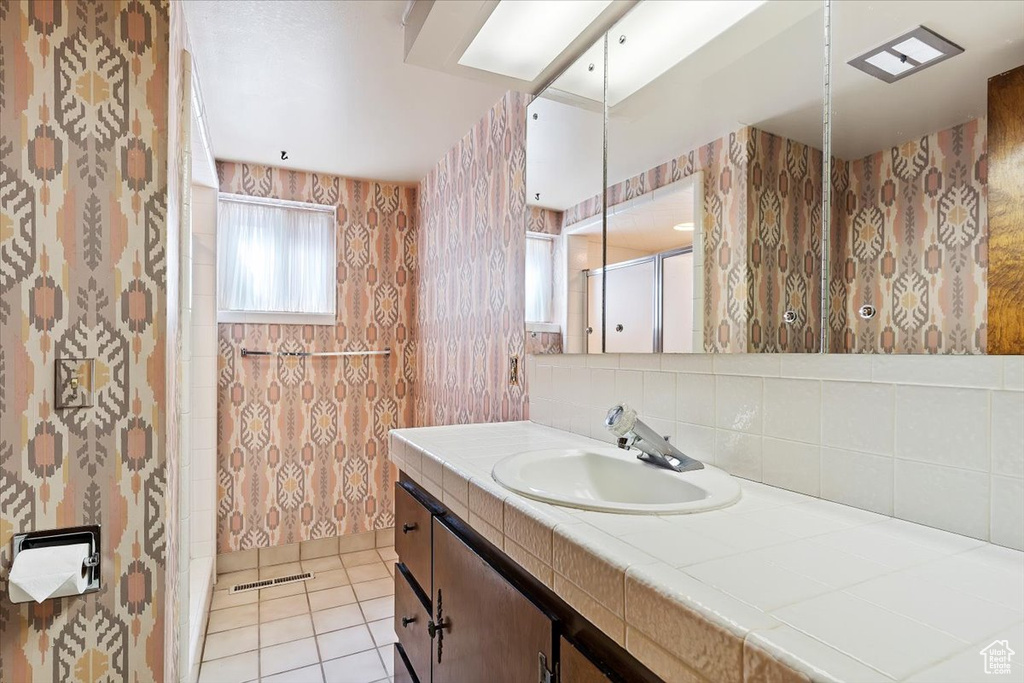 Bathroom with tasteful backsplash, tile floors, and large vanity