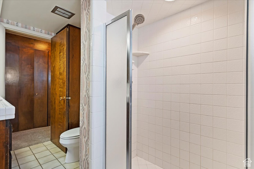 Bathroom featuring a shower with door, tile floors, and toilet