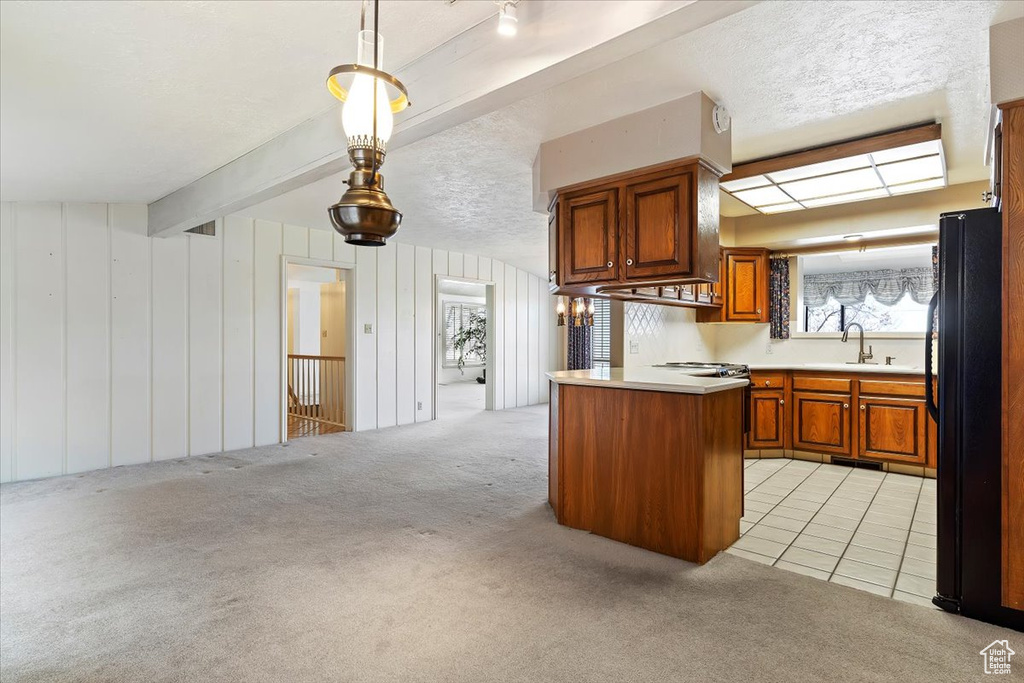 Kitchen with black fridge, light colored carpet, beamed ceiling, a textured ceiling, and hanging light fixtures