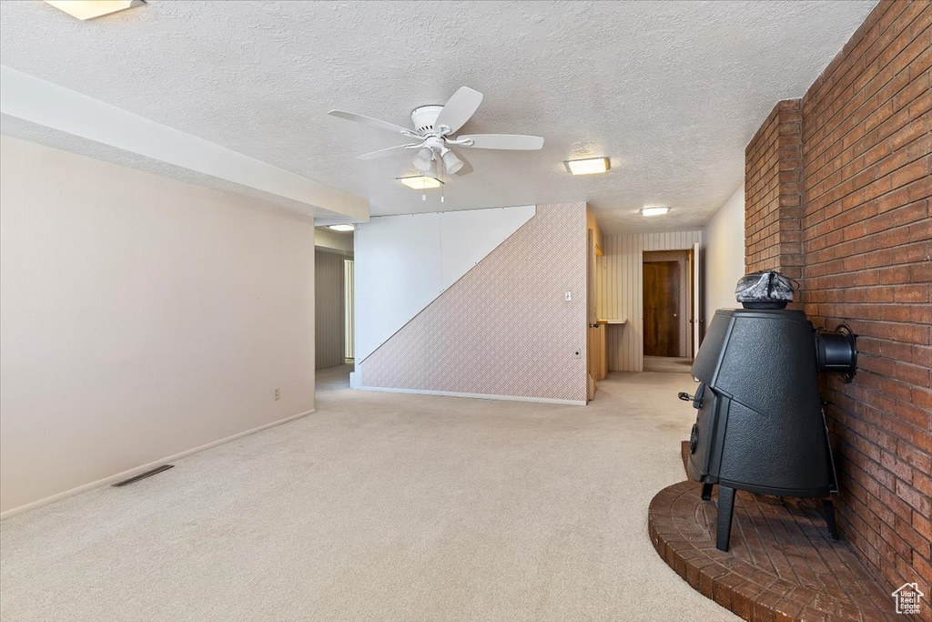Living area with ceiling fan, a textured ceiling, brick wall, and light colored carpet
