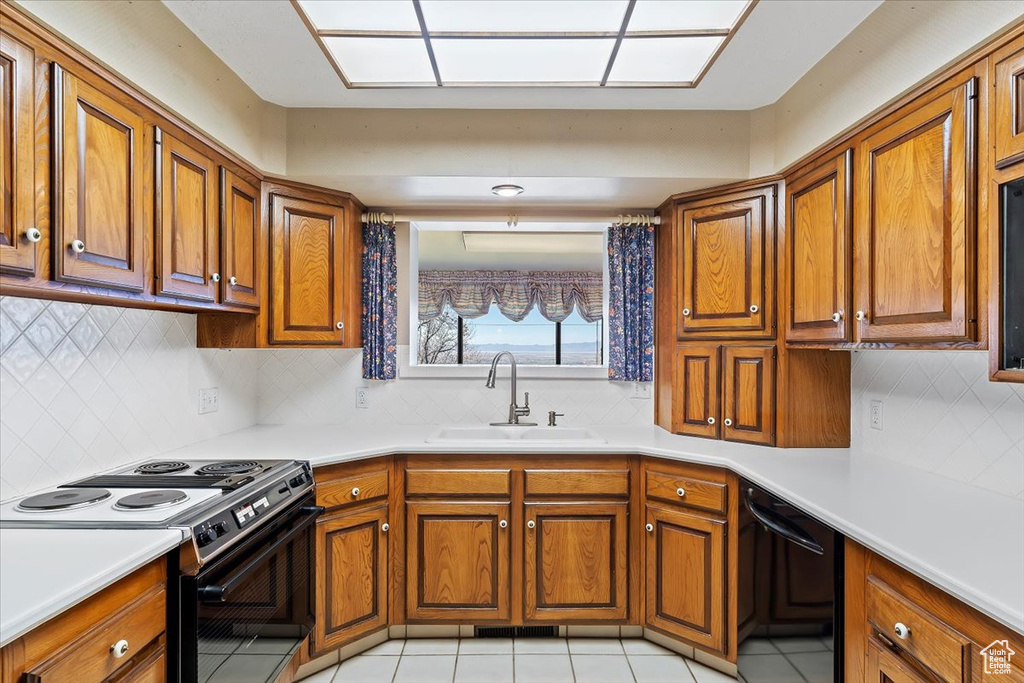 Kitchen featuring backsplash, white range, sink, and light tile floors