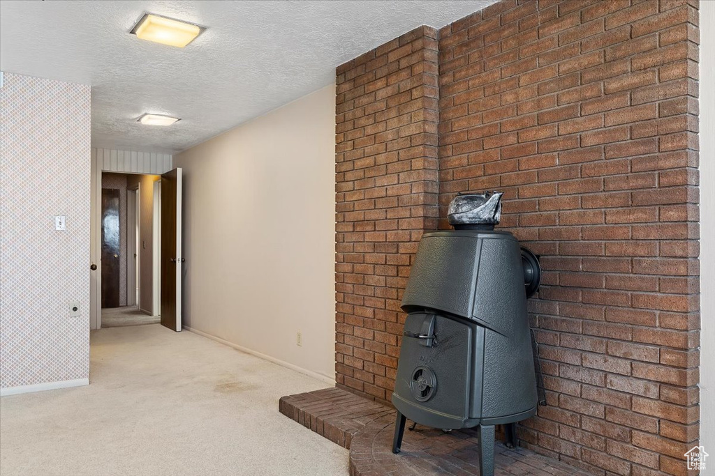 Interior space with light carpet, a textured ceiling, and brick wall