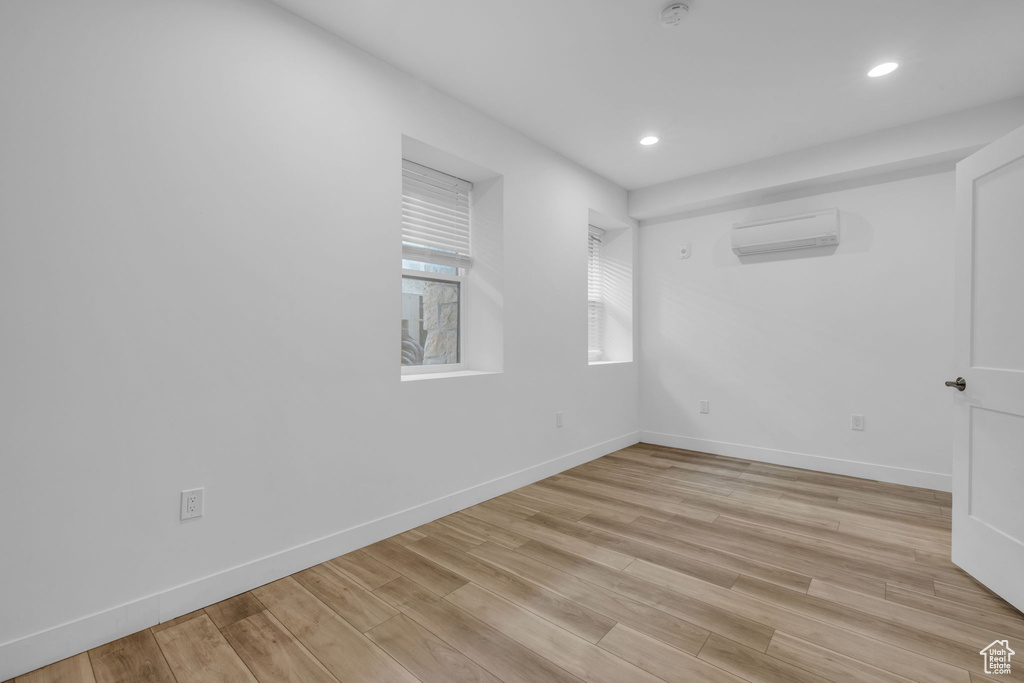 Unfurnished room with a wall mounted AC and light hardwood / wood-style flooring