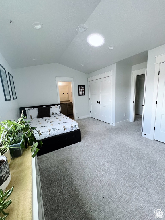 Bedroom featuring light colored carpet and vaulted ceiling