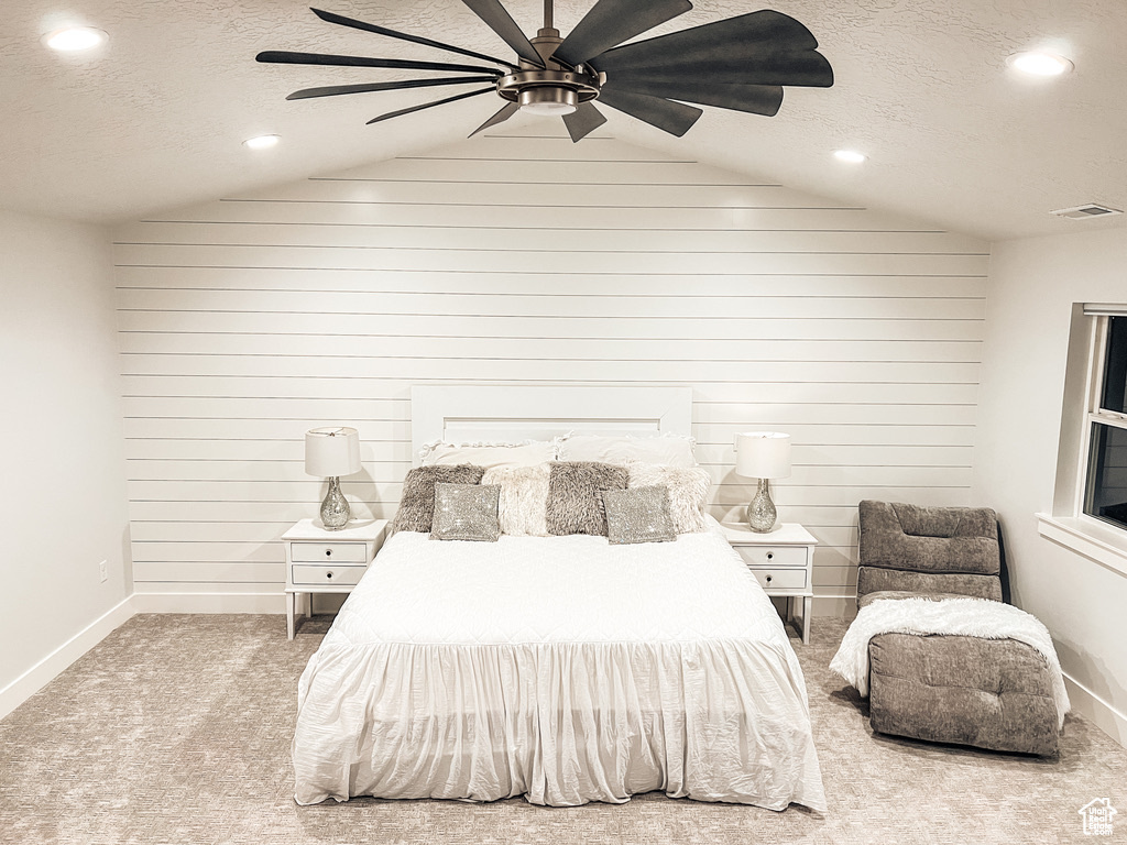 Carpeted bedroom with ceiling fan, a textured ceiling, and vaulted ceiling