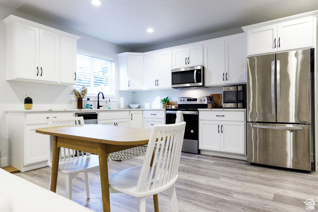 Kitchen featuring white cabinets, appliances with stainless steel finishes, and light hardwood / wood-style floors