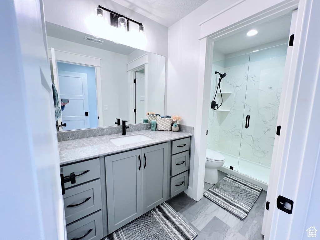 Bathroom featuring vanity, tile floors, a shower with door, and toilet