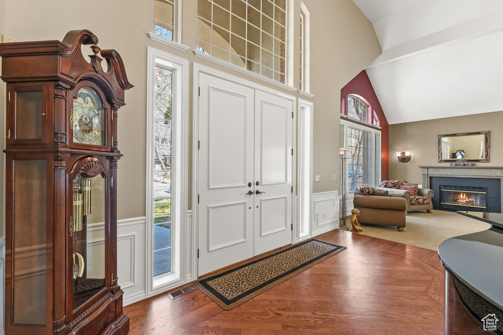 Foyer entrance featuring high vaulted ceiling and dark wood-type flooring