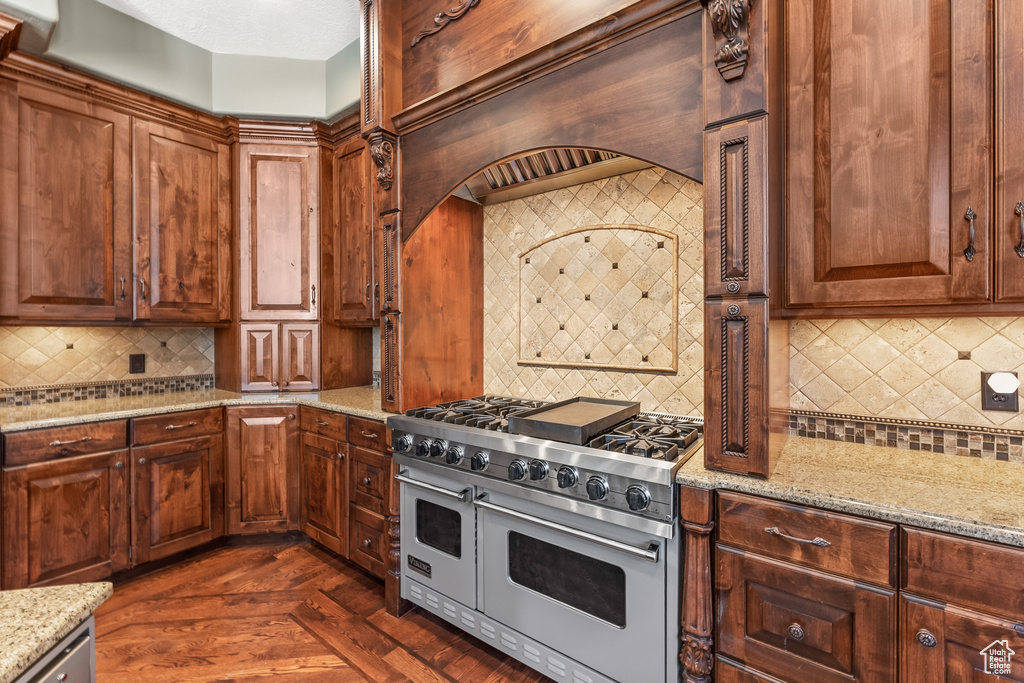 Kitchen with tasteful backsplash, double oven range, and light stone counters