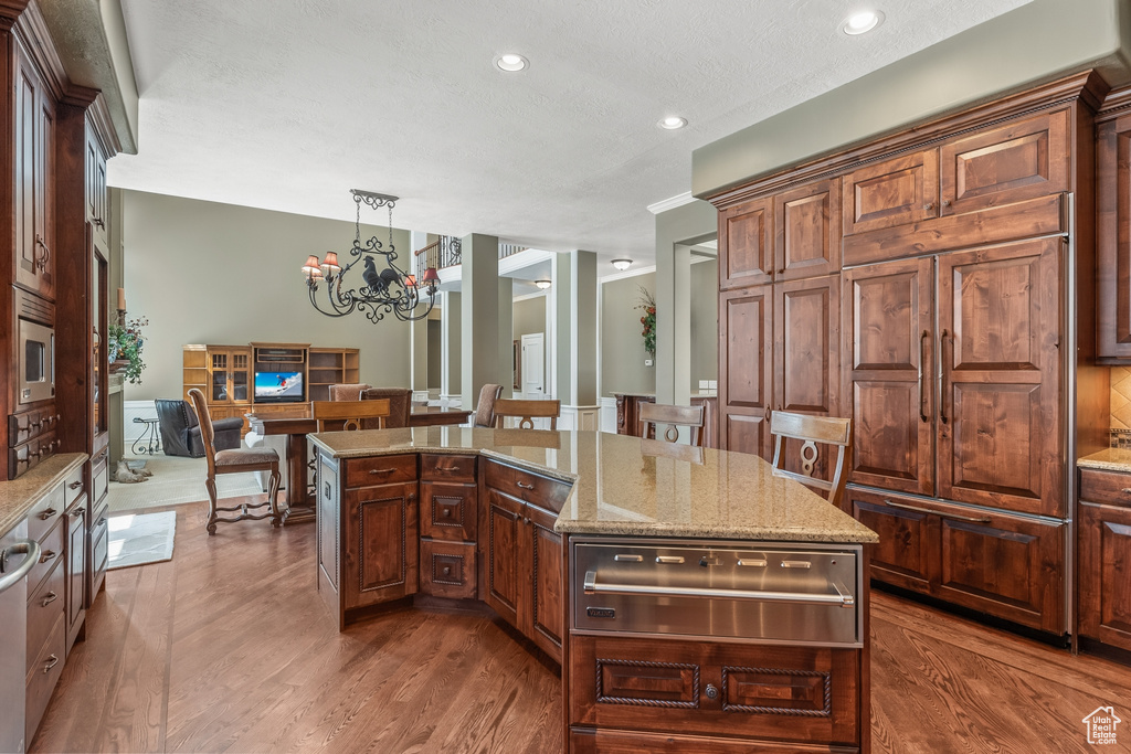 Kitchen with a chandelier, a kitchen island, decorative light fixtures, and hardwood / wood-style flooring