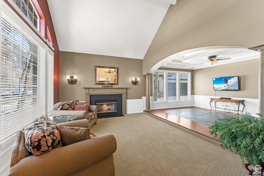 Carpeted living room with ceiling fan, a wealth of natural light, and high vaulted ceiling