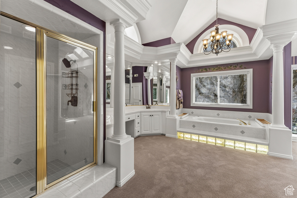 Bathroom with lofted ceiling, decorative columns, vanity, a chandelier, and separate shower and tub