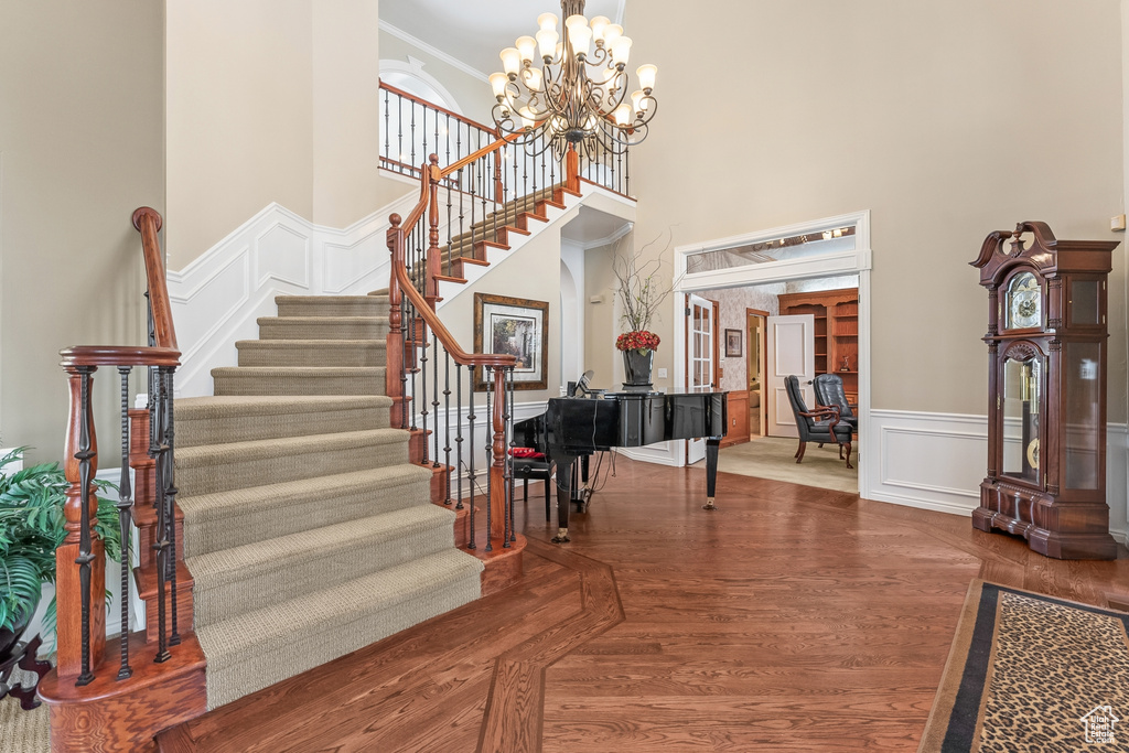 Stairway with dark hardwood / wood-style flooring, an inviting chandelier, and a high ceiling