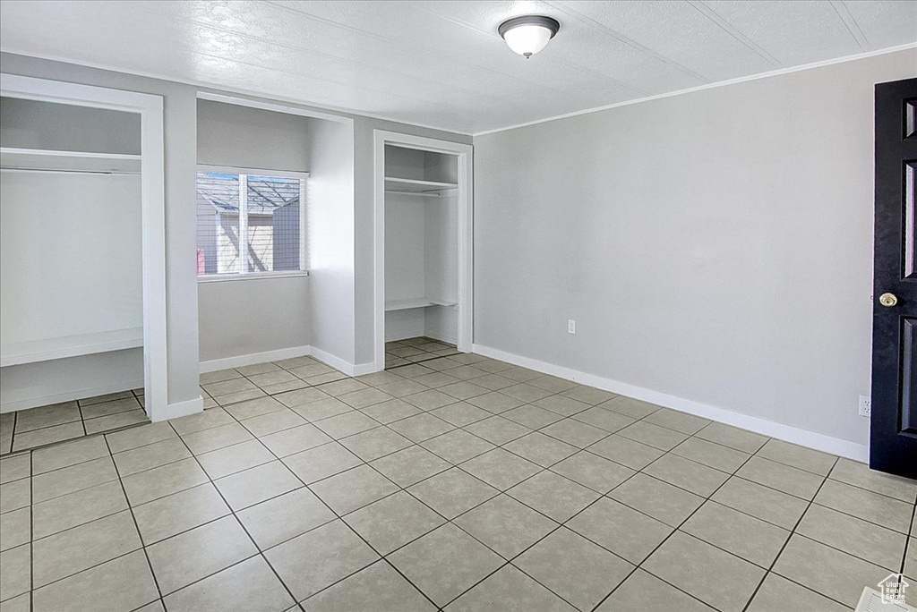 Unfurnished bedroom with light tile flooring and two closets