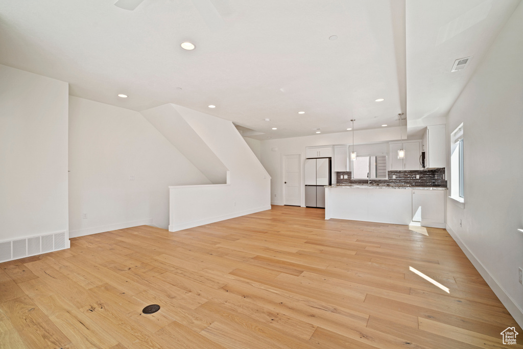 Unfurnished living room with sink and light hardwood / wood-style flooring