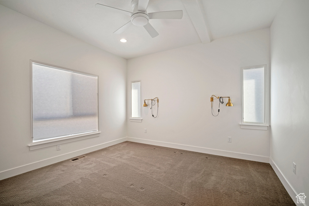 Carpeted empty room with ceiling fan and beamed ceiling
