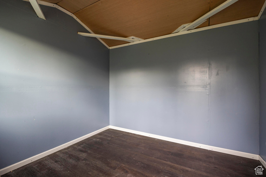 Unfurnished room featuring lofted ceiling and dark wood-type flooring