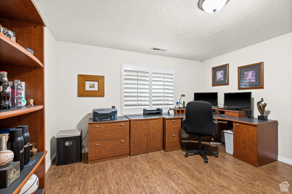 Office space with light hardwood / wood-style floors and a textured ceiling
