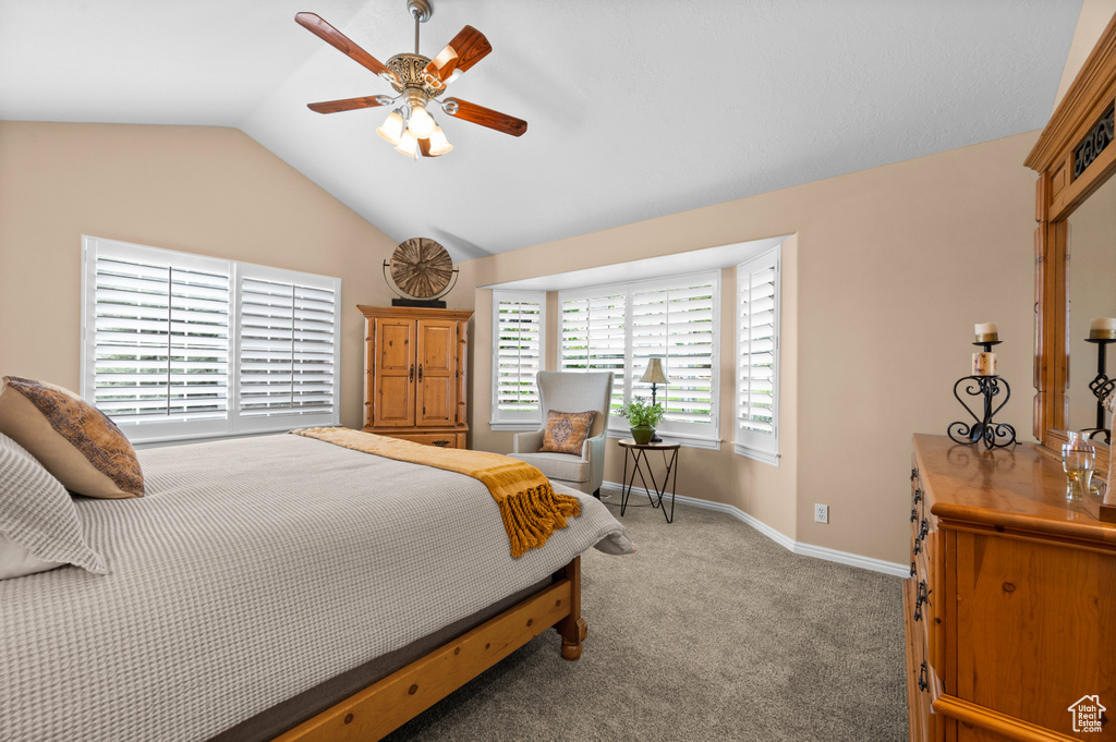 Carpeted bedroom featuring ceiling fan and vaulted ceiling