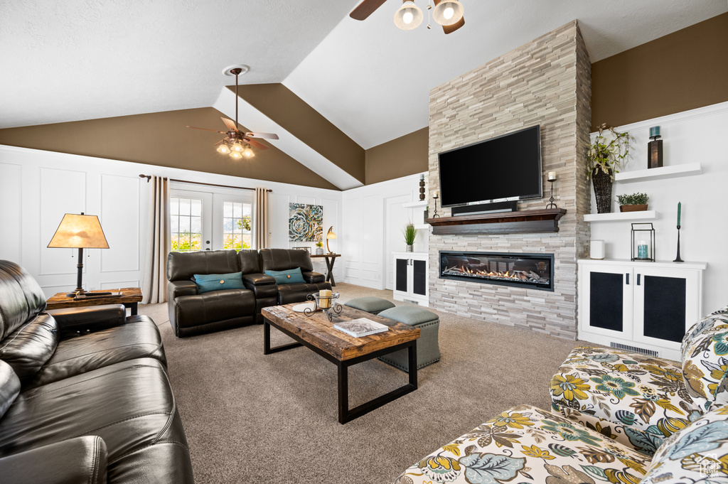 Living room with light carpet, ceiling fan, high vaulted ceiling, and a fireplace