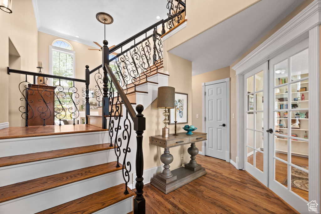 Stairway with crown molding, hardwood / wood-style flooring, and french doors