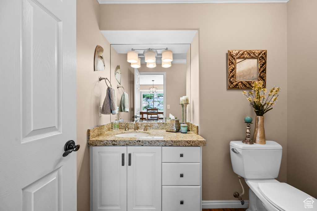 Bathroom featuring toilet, ornamental molding, and vanity
