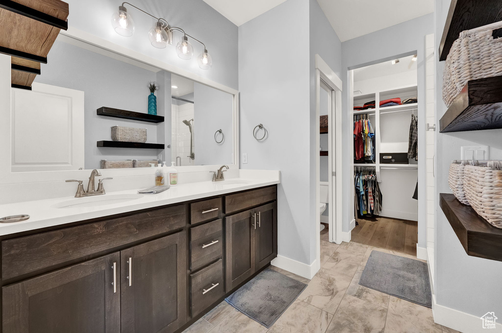 Bathroom featuring tile floors, toilet, double sink, and oversized vanity