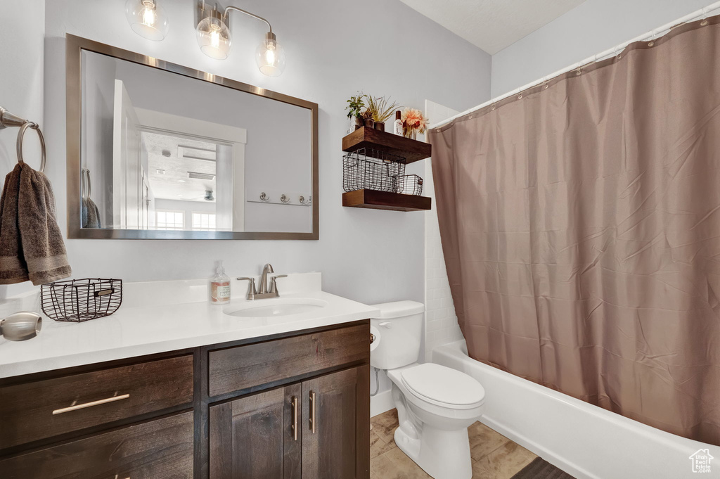 Full bathroom featuring toilet, large vanity, shower / tub combo, and tile flooring