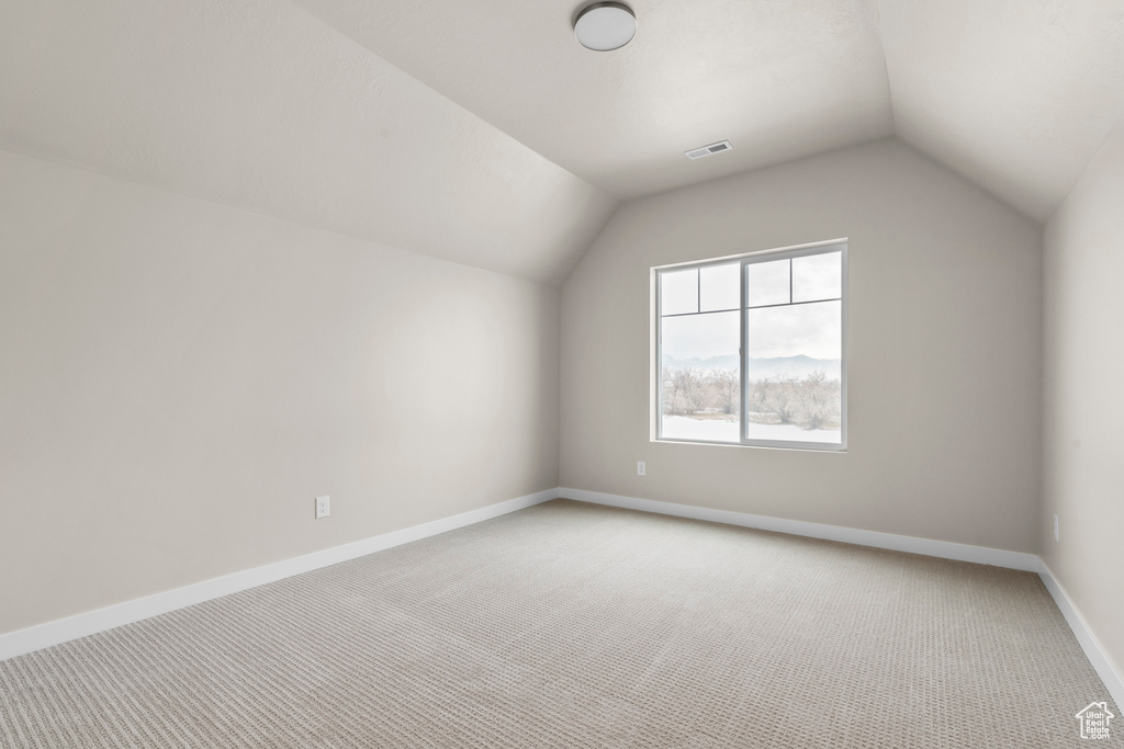 Additional living space featuring lofted ceiling and light colored carpet