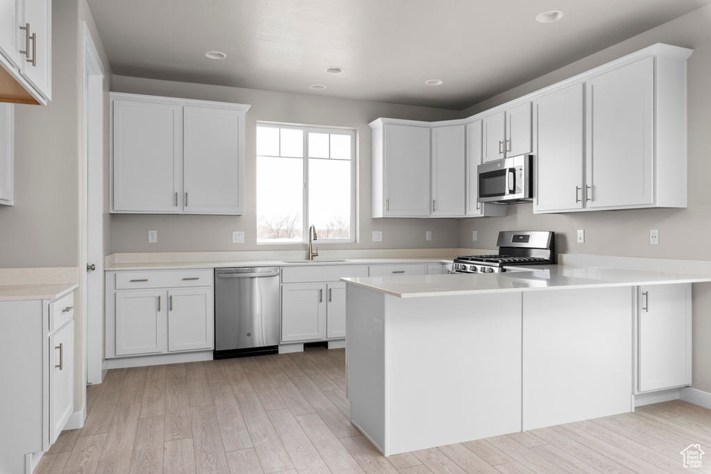 Kitchen featuring white cabinets, light hardwood / wood-style flooring, appliances with stainless steel finishes, and sink